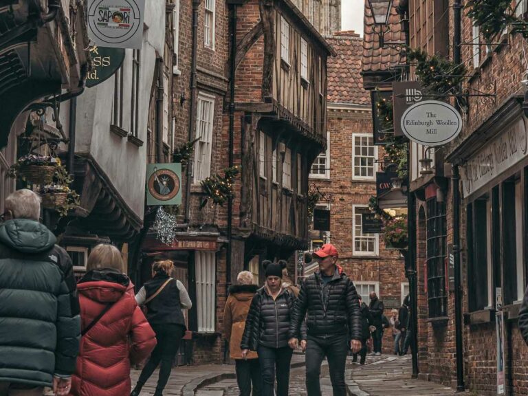 People walking down a medieval shopping street in York.