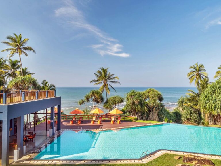 Resort pool area overlooks palm trees and ocean views.