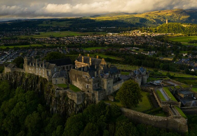 Aerial views of a historical Castle and it's grounds, with a town in the background.