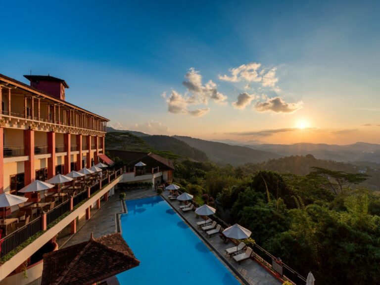 Mountain resort and pool with the mountains and sun setting in the distance.