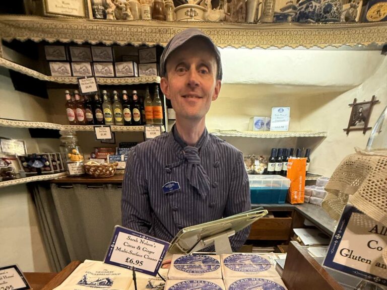 Local shopkeeper at gingerbread shop counter with handmade products and vintage shelving