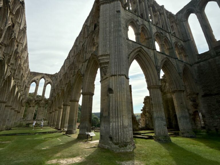 Small group walking tour exploring historic Gothic abbey ruins with towering stone columns and arches
