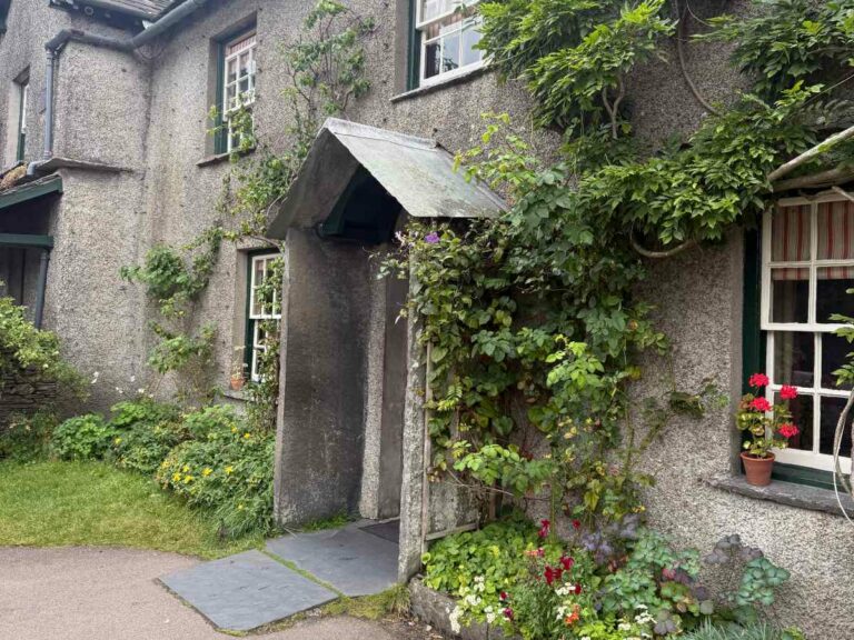 Traditional stone cottage with ivy-covered walls and flowering garden, European village architecture